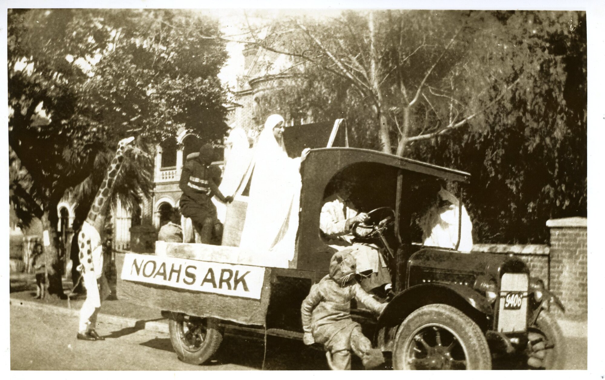 2297P - Commemoration Day Procession - 1922 - Float lorry named Noah's Ark with students dressed as animals and Noah's family - Student dressed as Giraffe walking behind