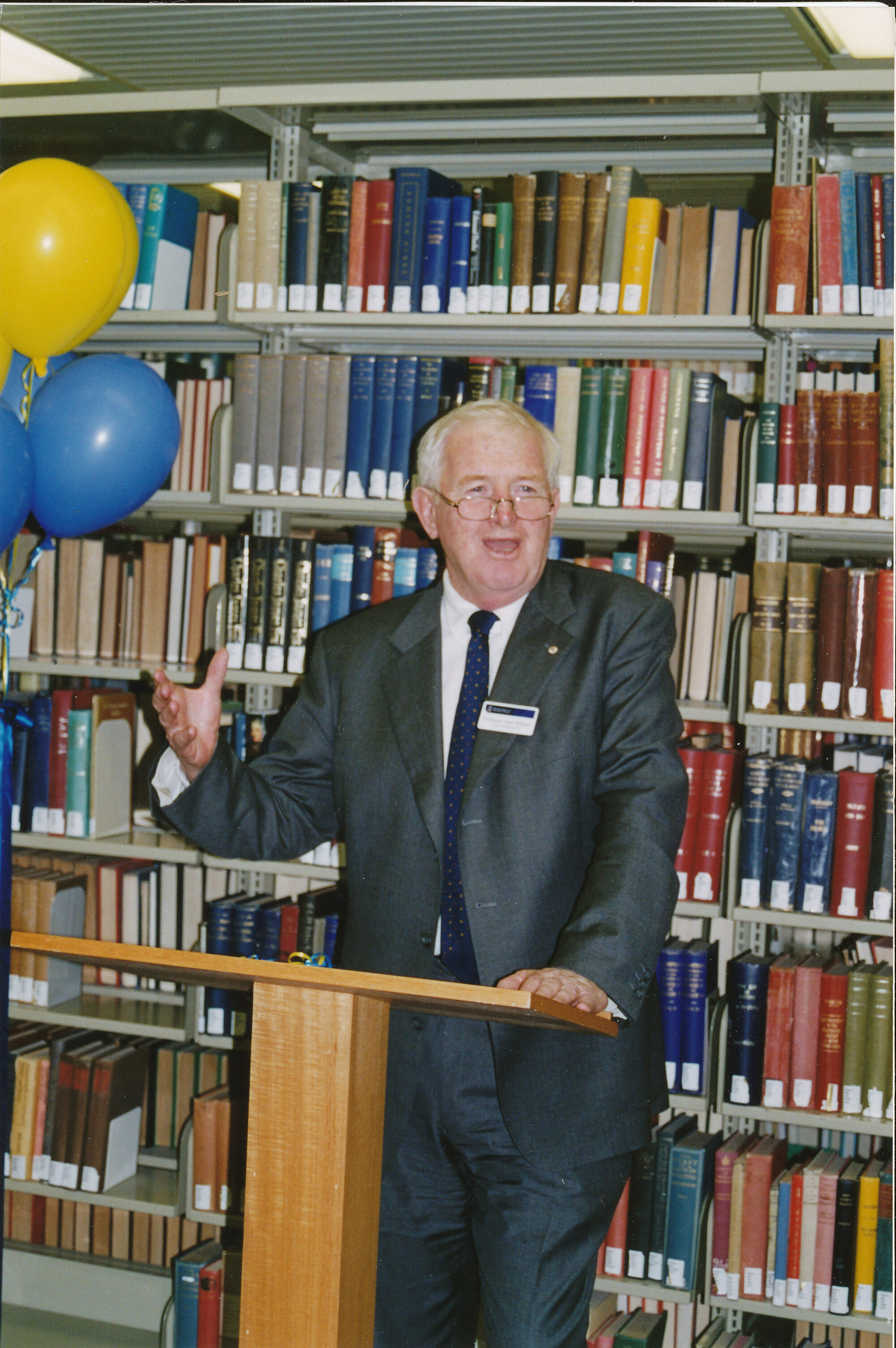 60538P - Vice Chancellor Professor Alan Robson - opening extensions / refurbishment Reid Library - standing at lectern in front of book shelves - balloons at left
